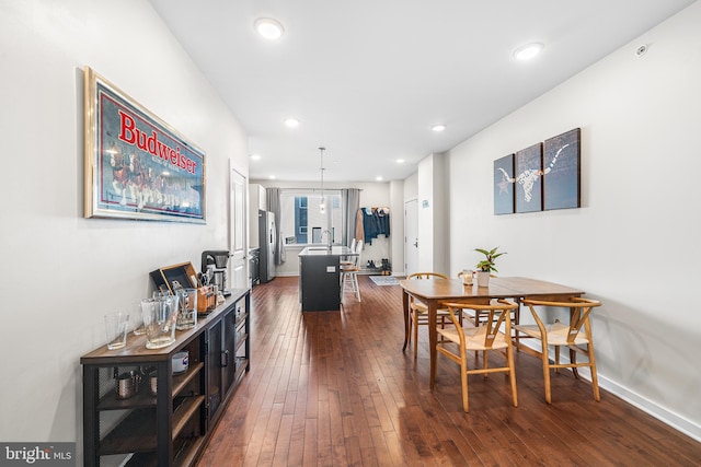 dining room with dark wood finished floors, recessed lighting, and baseboards