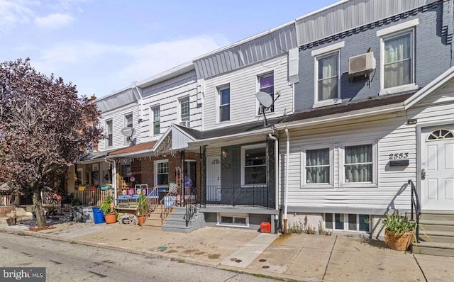 multi unit property featuring covered porch and a wall mounted air conditioner