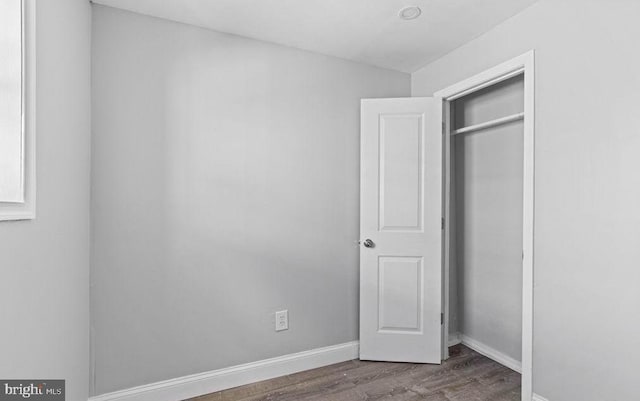 unfurnished bedroom featuring a closet, wood finished floors, and baseboards
