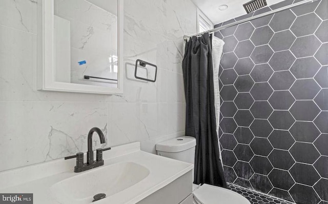 full bath featuring a stall shower, vanity, toilet, and tile walls