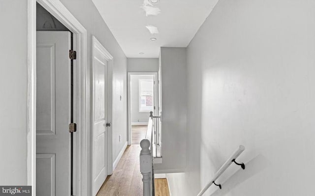corridor featuring baseboards and light wood finished floors