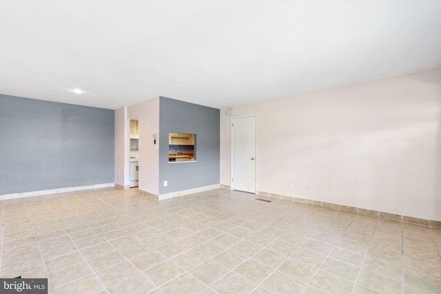 spare room with baseboards and light tile patterned floors