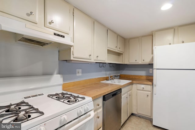 kitchen featuring white appliances, a sink, under cabinet range hood, light tile patterned floors, and cream cabinetry