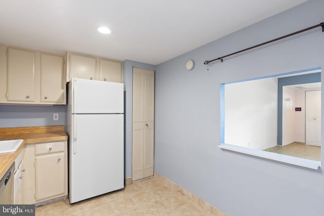 kitchen featuring freestanding refrigerator, cream cabinets, light countertops, recessed lighting, and a sink