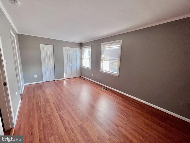 2904 11th St NW, Washington, DC 20001 - unfurnished bedroom featuring baseboards, visible vents, ornamental molding, multiple closets, and light wood-type flooring