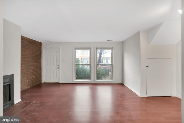 2904 11th St NW, Washington, DC 20001 - unfurnished living room with visible vents, brick wall, baseboards, a fireplace with flush hearth, and wood finished floors