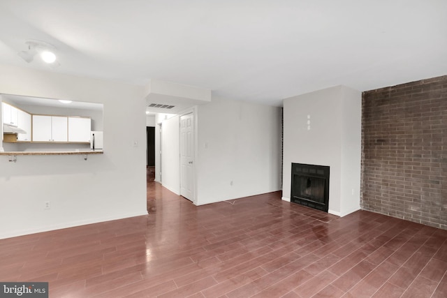 2904 11th St NW, Washington, DC 20001 - unfurnished living room featuring visible vents, a fireplace, brick wall, and wood finished floors