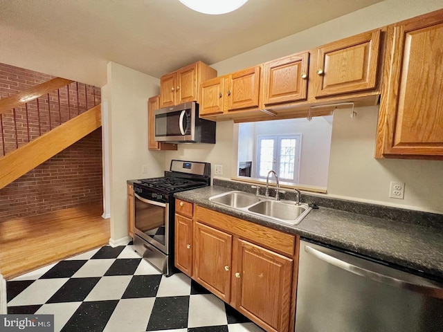 2904 11th St NW, Washington, DC 20001 - kitchen with a sink, dark countertops, stainless steel appliances, brick wall, and light floors