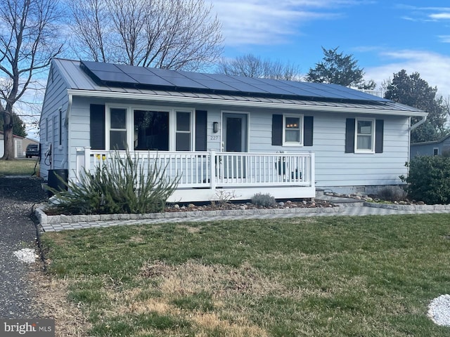 view of front facade featuring a standing seam roof, a porch, a front lawn, and metal roof
