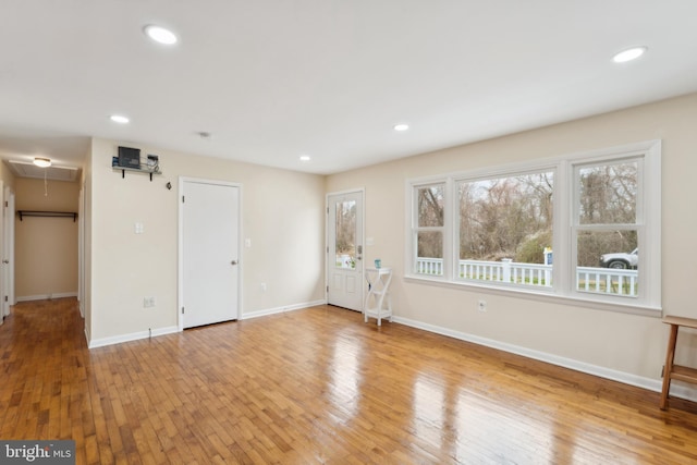 unfurnished living room with baseboards, recessed lighting, attic access, and light wood-style floors