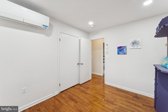 interior space featuring an AC wall unit, hardwood / wood-style flooring, recessed lighting, and baseboards