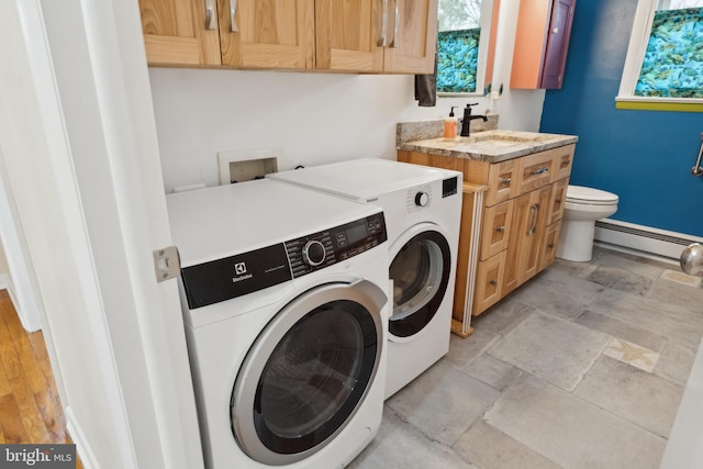 washroom featuring stone tile floors, laundry area, a sink, washer and dryer, and baseboard heating