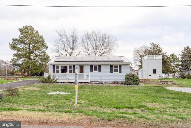 view of front of home with a front lawn, a porch, and roof mounted solar panels
