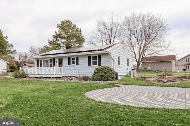 single story home with roof mounted solar panels, a vegetable garden, a front lawn, and fence
