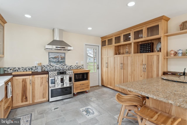 kitchen featuring range with two ovens, wall chimney exhaust hood, black microwave, and stone finish floor