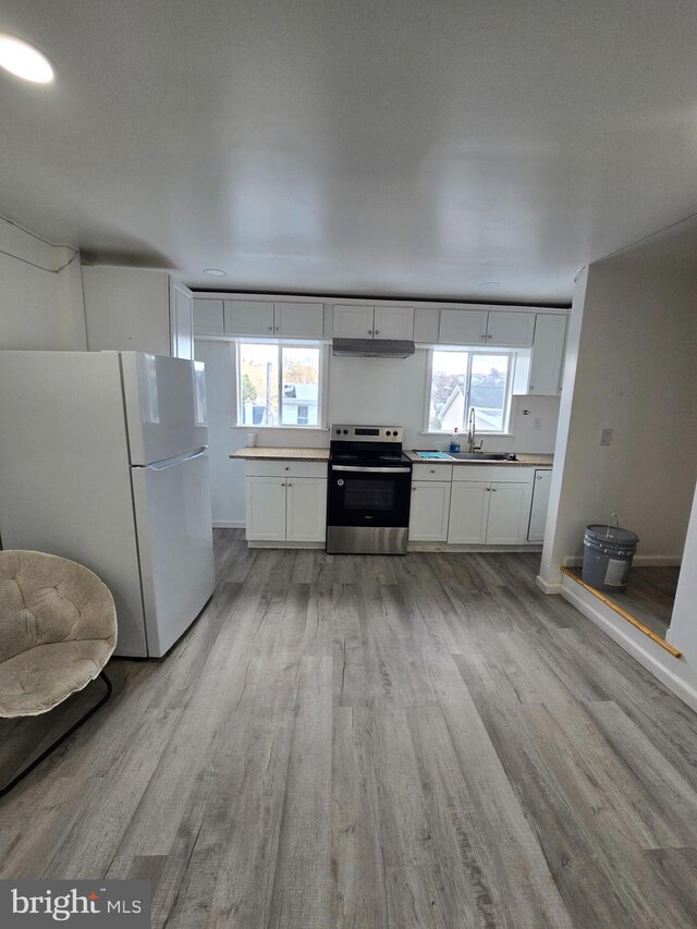 325 W Washington St, Tamaqua, PA 18252 - kitchen featuring stainless steel electric stove, freestanding refrigerator, a sink, light wood-style floors, and under cabinet range hood