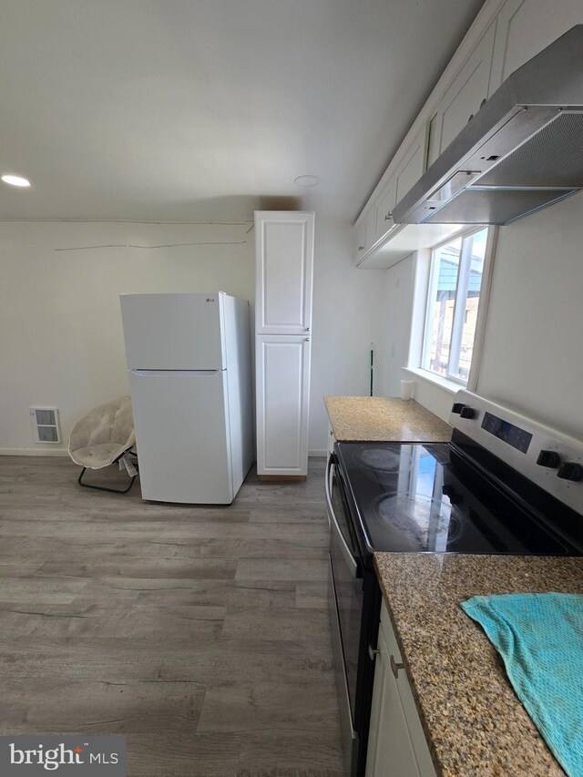 325 W Washington St, Tamaqua, PA 18252 - kitchen featuring under cabinet range hood, stainless steel electric range oven, freestanding refrigerator, wood finished floors, and white cabinets