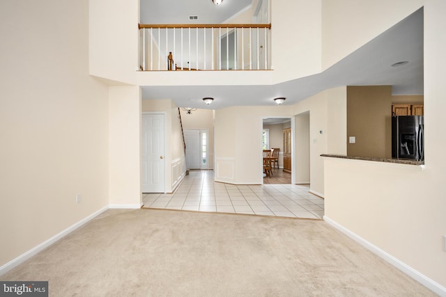11 Ashbrook Rd, Stafford, VA 22554 - unfurnished living room featuring light tile patterned floors, light colored carpet, baseboards, and a high ceiling