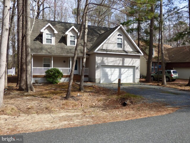 cape cod-style house featuring driveway, covered porch, and a garage