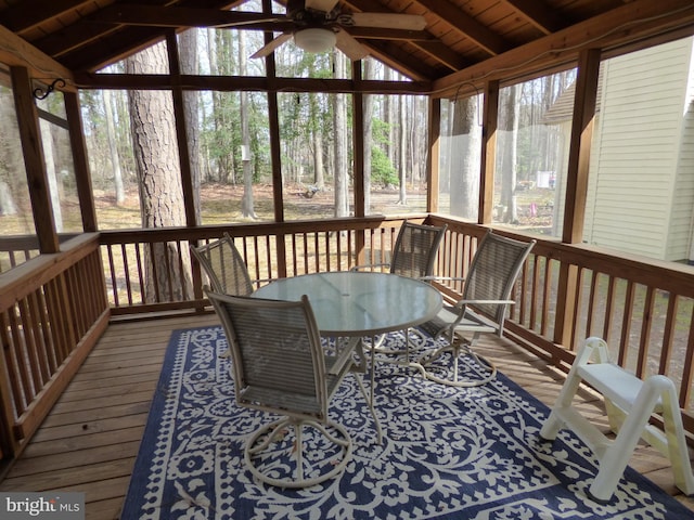 sunroom featuring a ceiling fan, outdoor dining space, and beam ceiling