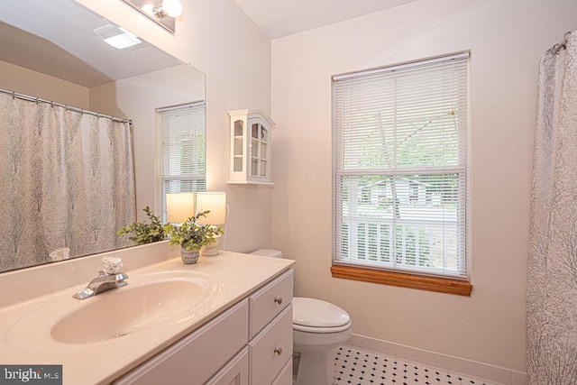 bathroom with toilet, baseboards, a healthy amount of sunlight, and vanity