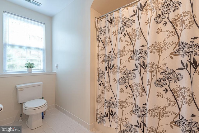 bathroom featuring toilet, a wealth of natural light, baseboards, and tile patterned floors
