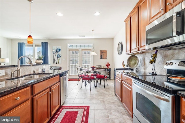kitchen featuring hanging light fixtures, a sink, brown cabinets, and appliances with stainless steel finishes