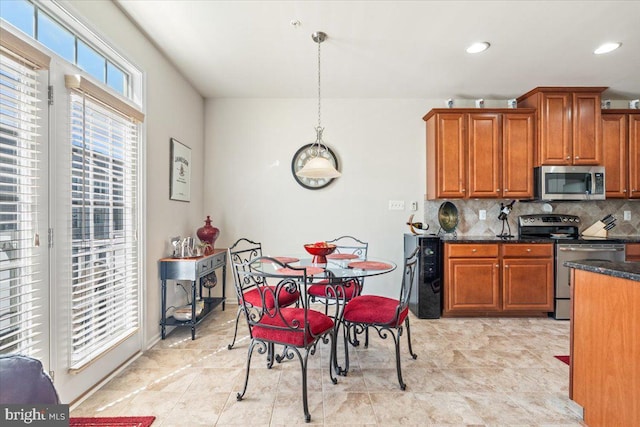 kitchen with brown cabinets, decorative light fixtures, decorative backsplash, and appliances with stainless steel finishes