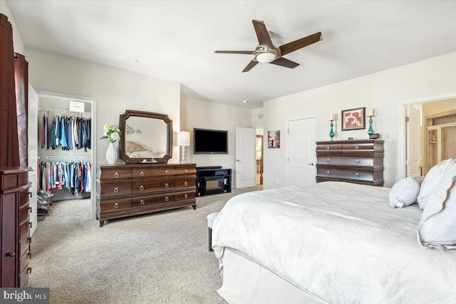 bedroom featuring a spacious closet, carpet, a closet, and ceiling fan