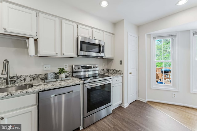 kitchen featuring white cabinetry, stainless steel appliances, wood finished floors, and a sink