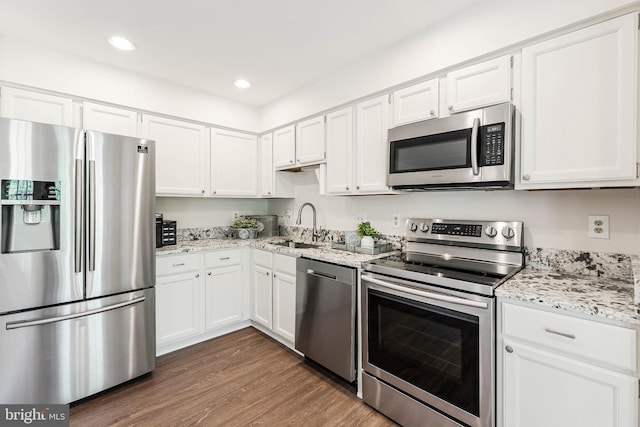 kitchen with a sink, white cabinets, appliances with stainless steel finishes, and dark wood finished floors