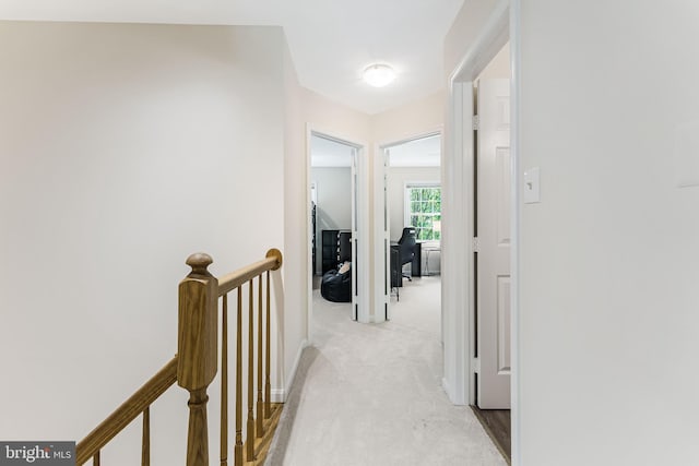 hallway with an upstairs landing and light carpet