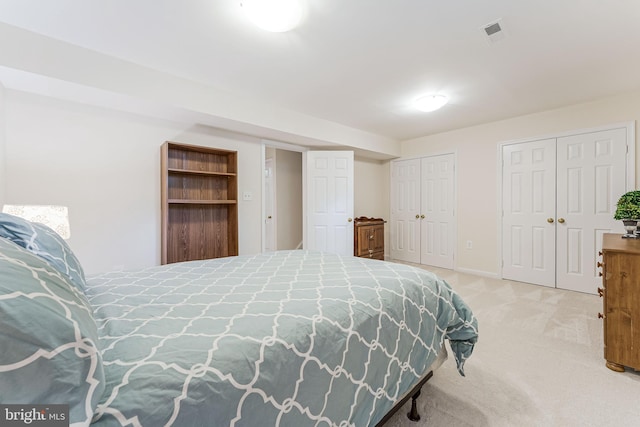 bedroom with visible vents, multiple closets, carpet flooring, and baseboards