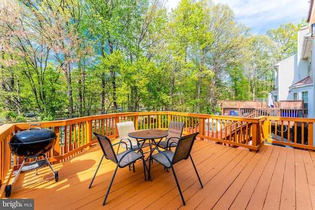 wooden deck with outdoor dining area and grilling area