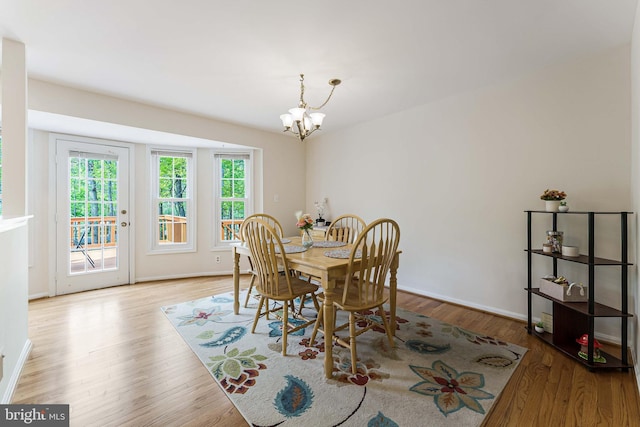 dining area with baseboards, wood finished floors, and a notable chandelier