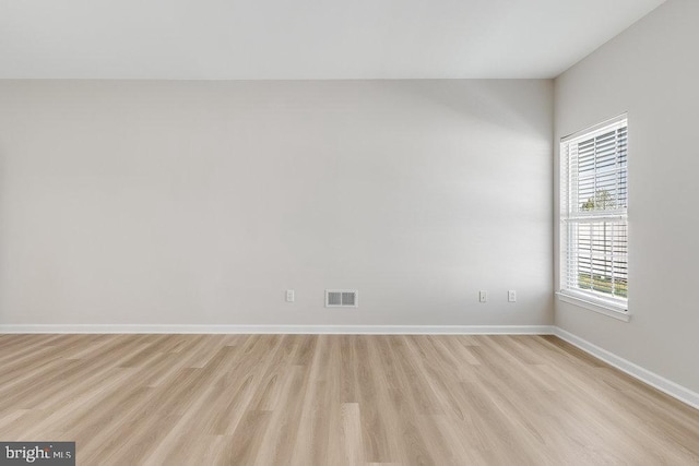 empty room featuring light wood-type flooring, baseboards, and visible vents