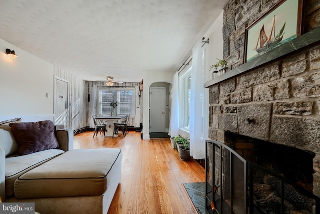 living area featuring a stone fireplace and light wood-type flooring