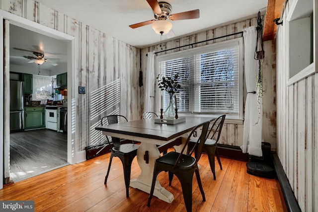dining room featuring ceiling fan, light wood finished floors, and wallpapered walls