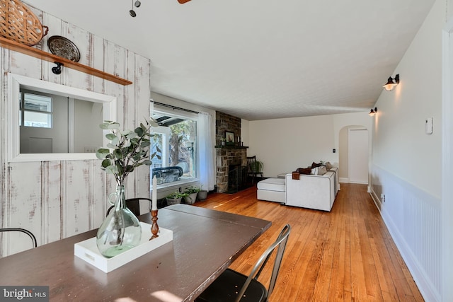 dining area featuring light wood-style flooring, arched walkways, and baseboards