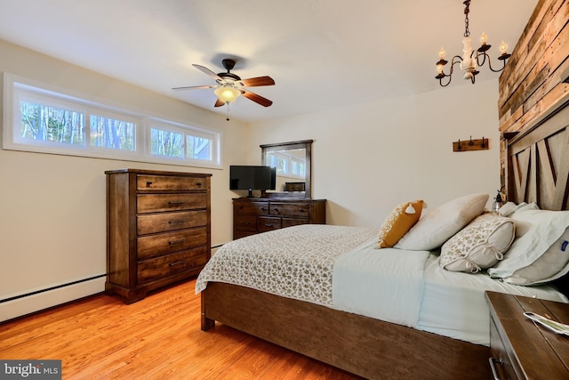 bedroom featuring light wood-type flooring, a baseboard heating unit, and ceiling fan with notable chandelier