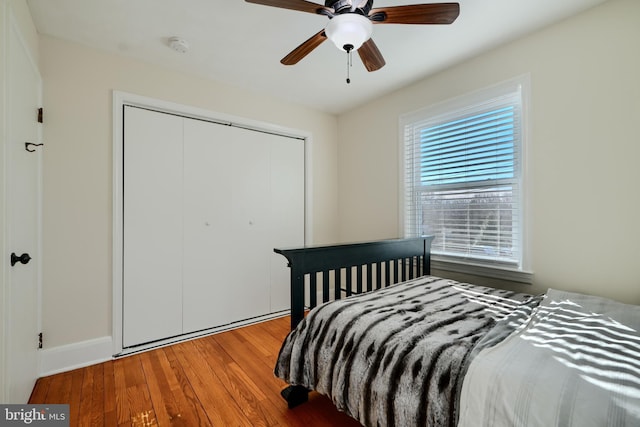 bedroom featuring a closet, wood finished floors, baseboards, and a ceiling fan