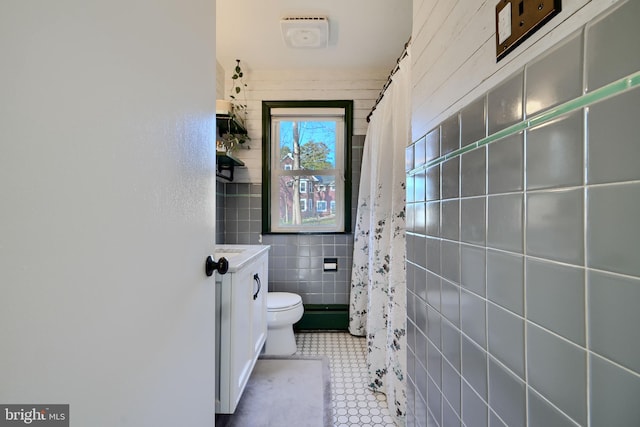 bathroom with toilet, vanity, a shower with shower curtain, and tile walls