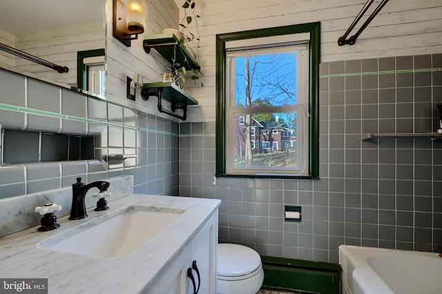 bathroom with vanity, toilet, a washtub, decorative backsplash, and tile walls