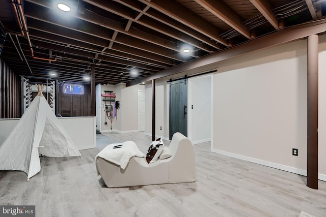 finished basement featuring a barn door, baseboards, and wood finished floors