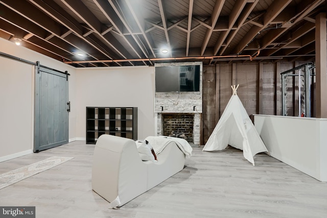 basement with a barn door, baseboards, and wood finished floors