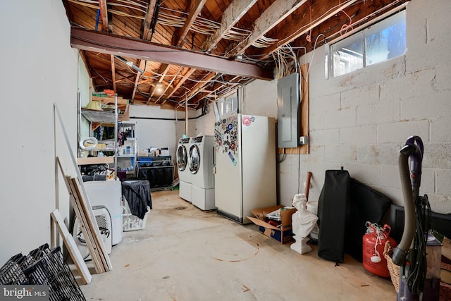 below grade area featuring freestanding refrigerator, washer and dryer, electric panel, and concrete block wall