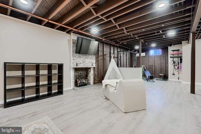 below grade area featuring wood finished floors and a stone fireplace