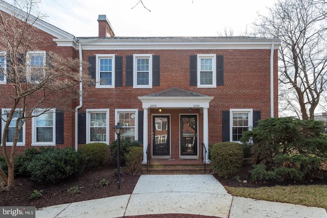 townhome / multi-family property featuring a chimney and brick siding