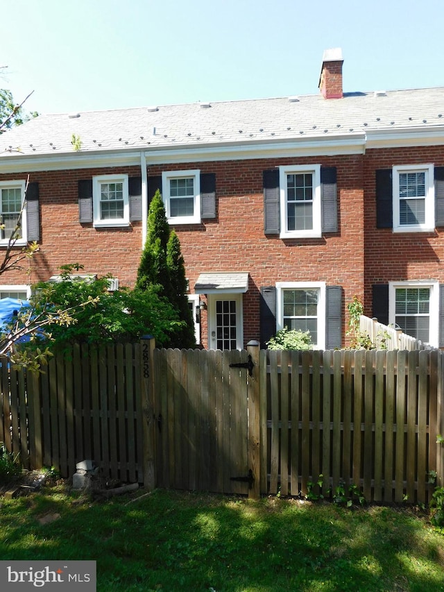 exterior space with brick siding, fence, and a chimney