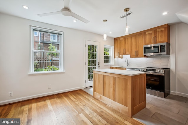 2858 S Abingdon St, Arlington, VA 22206 - kitchen featuring appliances with stainless steel finishes, light countertops, light wood-style floors, backsplash, and a center island